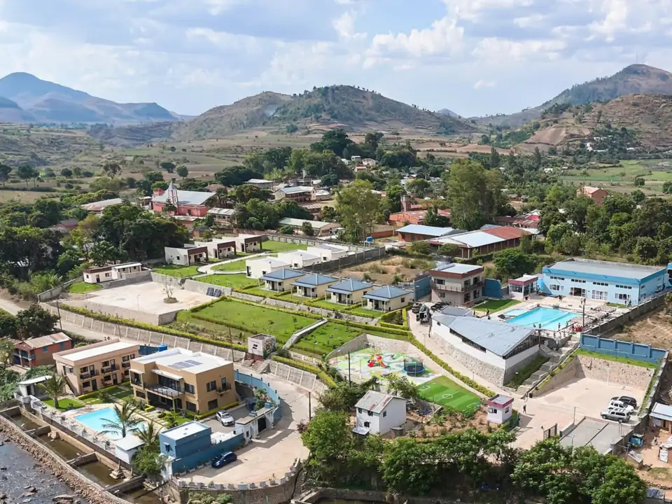 Vue aérienne d'ensemble du resort Riarano et du village d'Ampefy, collines volcaniques à l'horizon