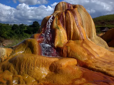 Geyser d'Analavory : eau ruisselant sur des concrétions minérales orangées